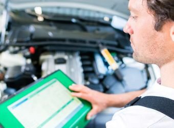 Mechanic with diagnostic tool in car workshop