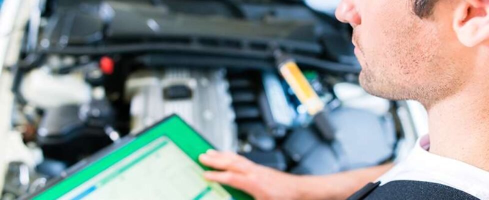 Mechanic with diagnostic tool in car workshop
