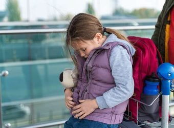 Little caucasian child girl sitting with her backpack and waiting for her first flight. Happy childhood concept. Stock photo