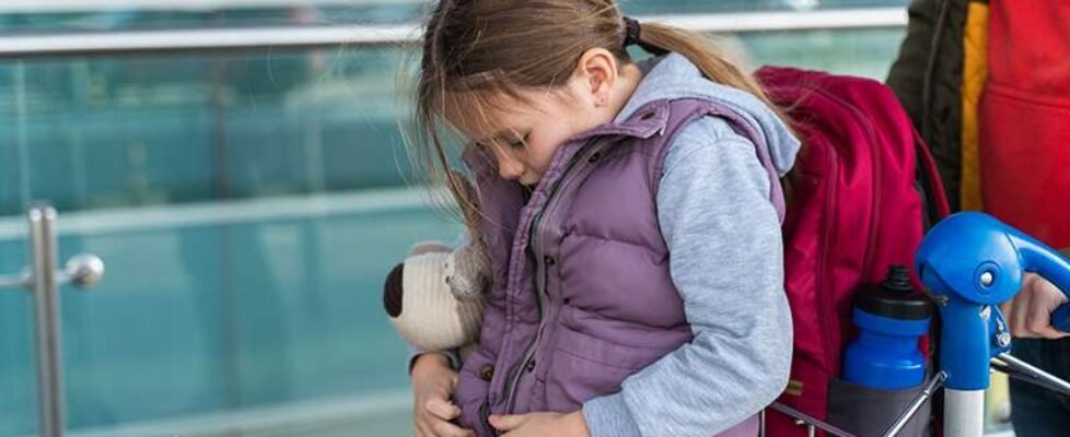 Little caucasian child girl sitting with her backpack and waiting for her first flight. Happy childhood concept. Stock photo