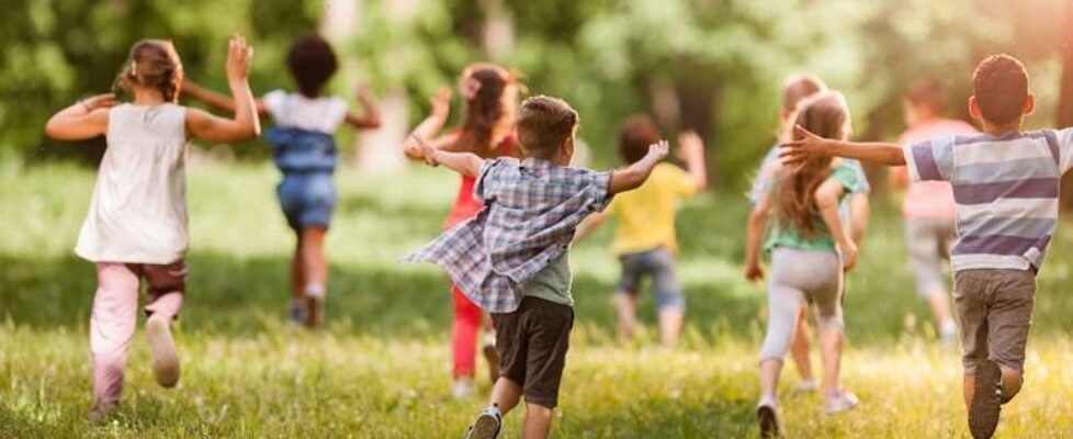 Rear view of large group of children running in springtime.