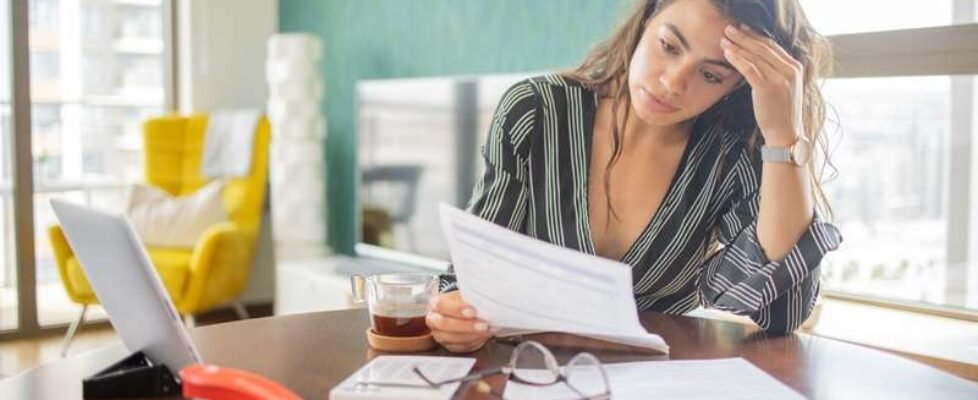 Young woman using calculator while going through bills and home finances