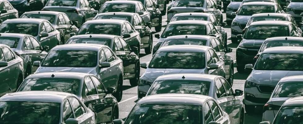 Rows of a new cars parked in a distribution center on a car factory on a sunny day. Parking in the open air.