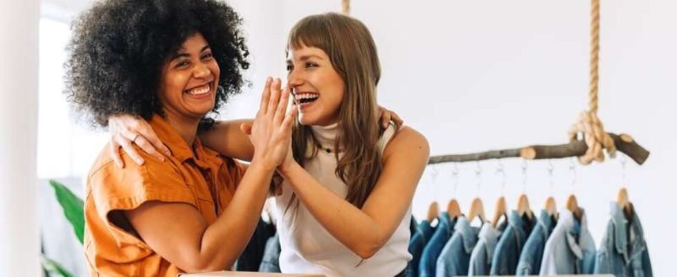 Cheerful online store owners high-fiving each other in their thrift store
