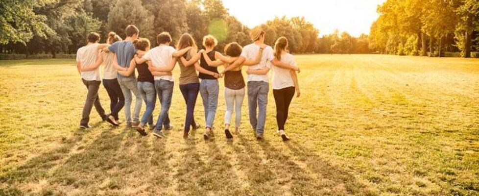 Group of teenagers walking in a field holding together