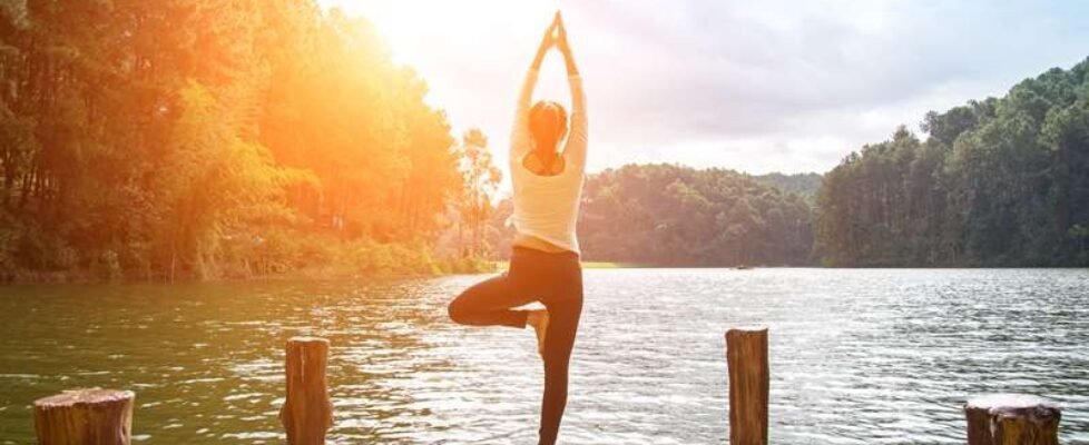 Healthy woman practicing yoga on the bridge in the nature