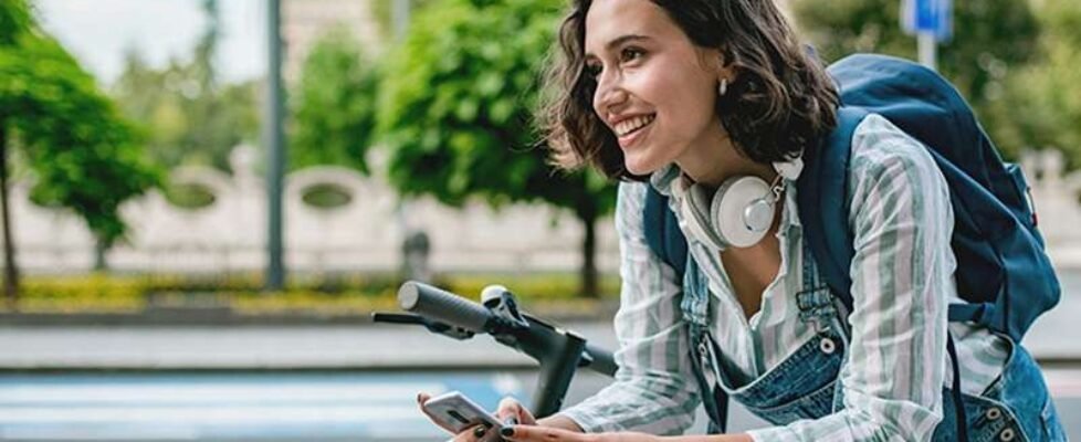 Young woman with electric scooter on the street using smart phone